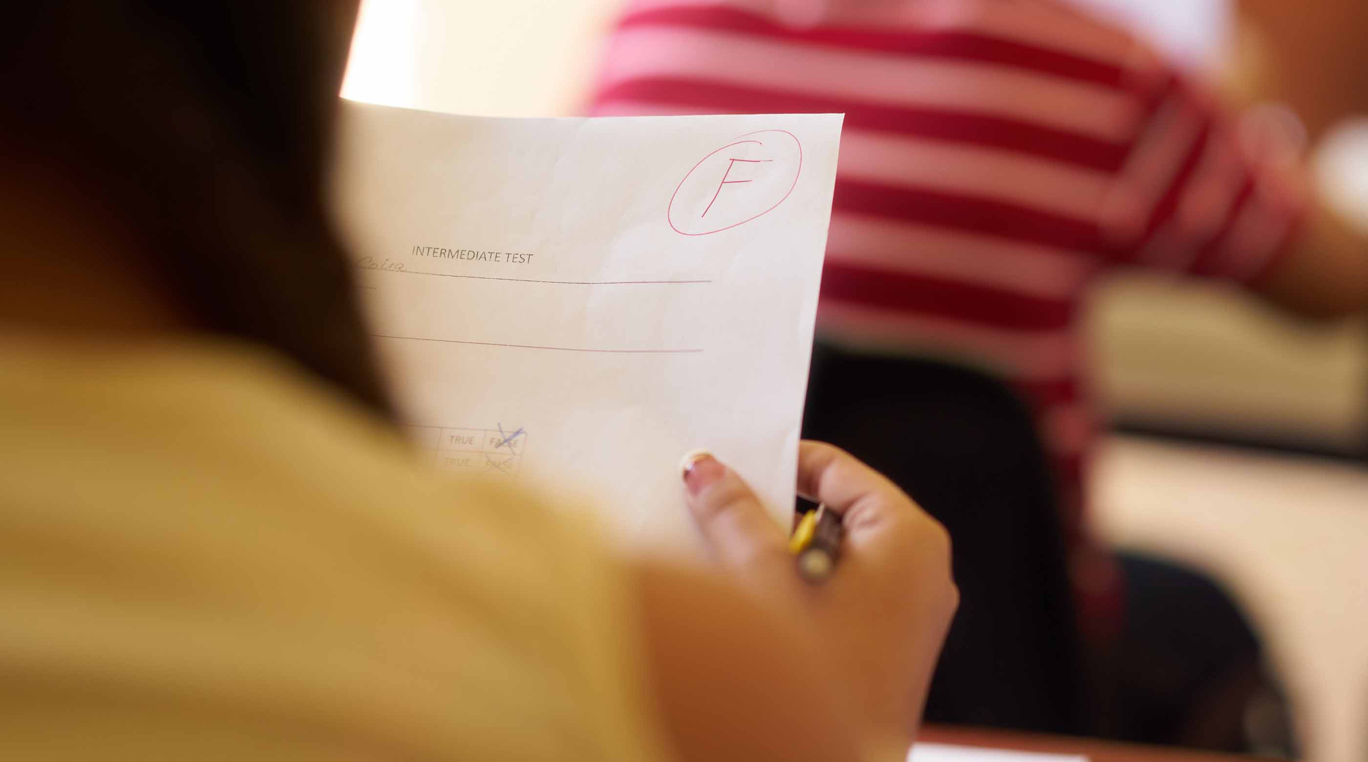 Student looking at a report card with an F grade